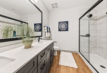 A bathroom with a white counter top and a wooden floor.